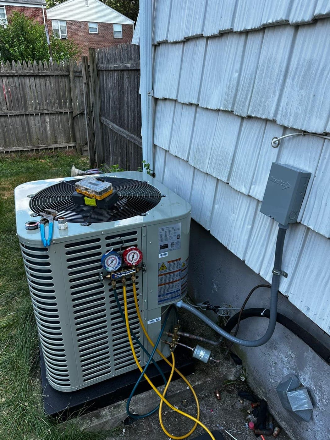 Technician gauges connected to a residential air conditioning condenser during service