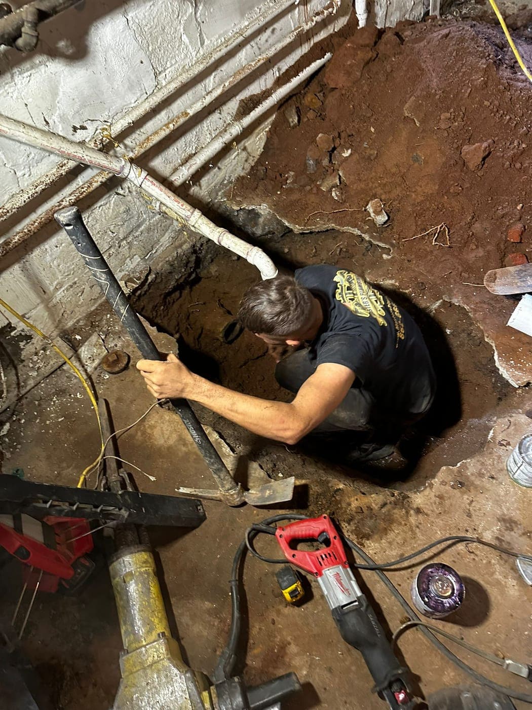 Technician replacing a sewer line under a basement floor