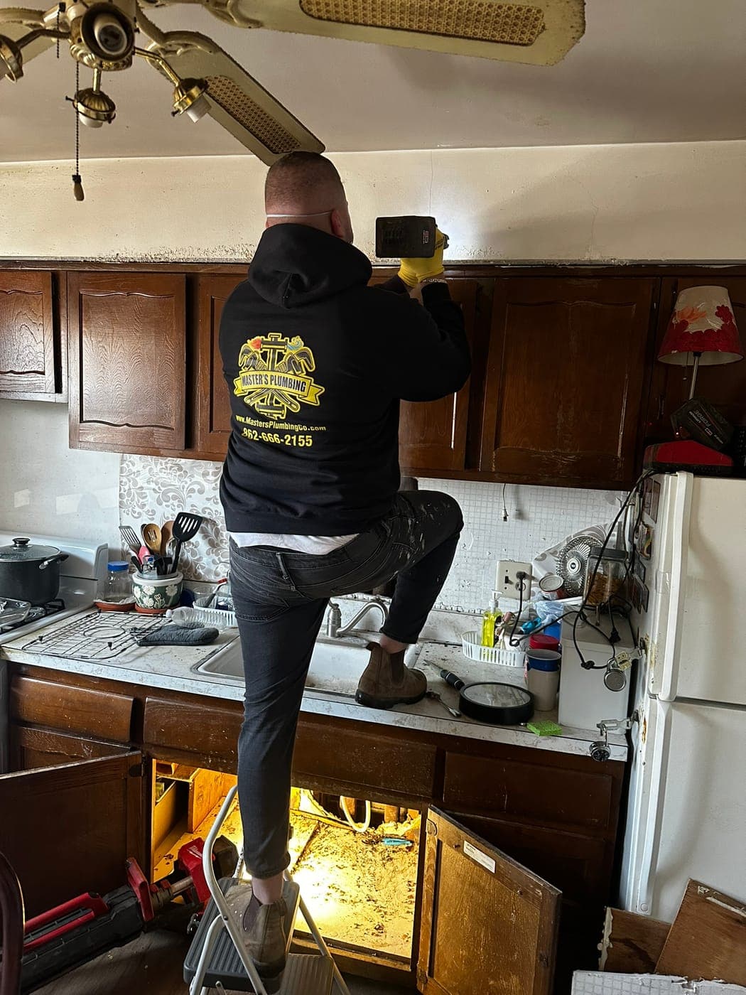 Master's Plumbing technician repairing a kitchen plumbing line
