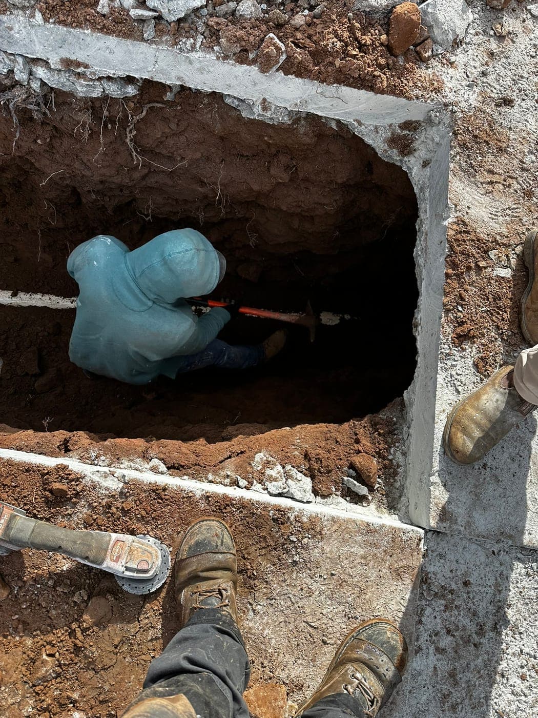Master's Plumbing technician hand-digging a sewer trench