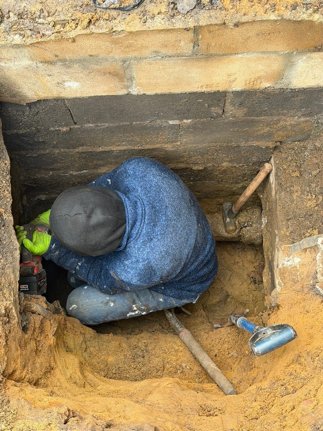 Technician in a safety vest working in a water line trench